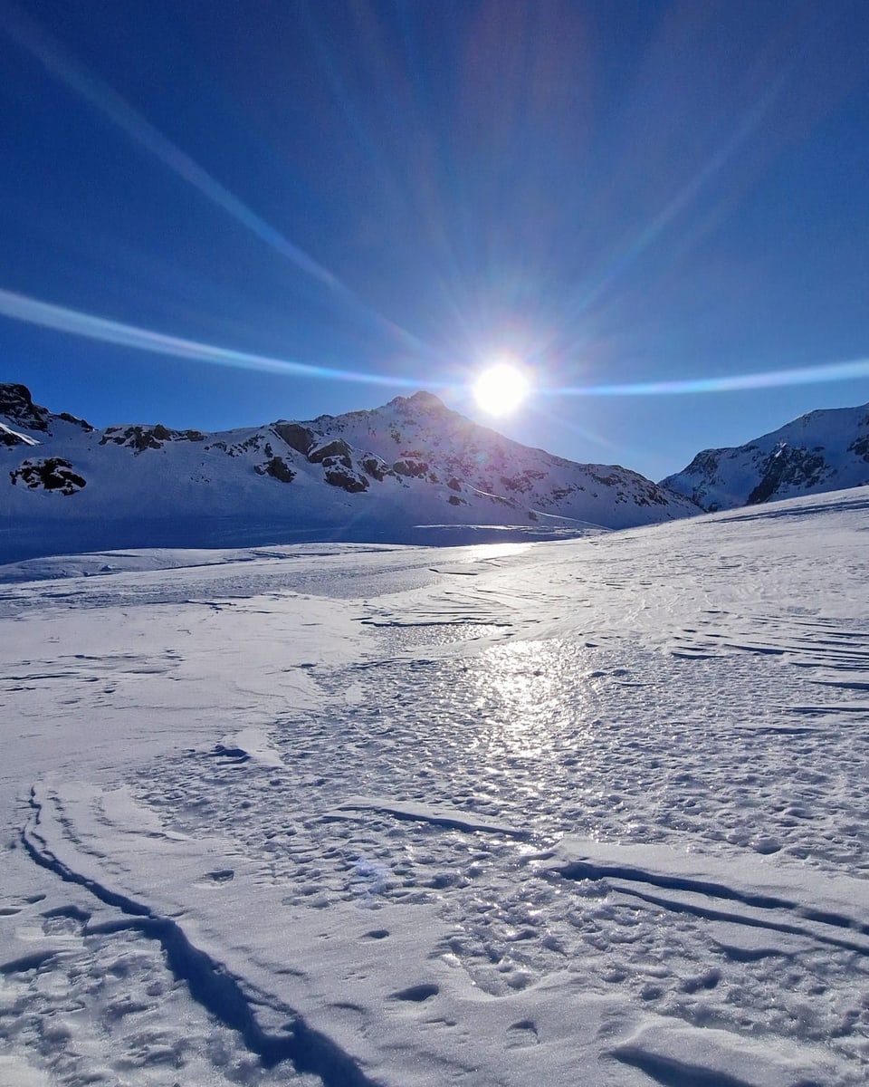 Eine mit Schnee verzierte Berglandschaft mit der strahlenden Sonne