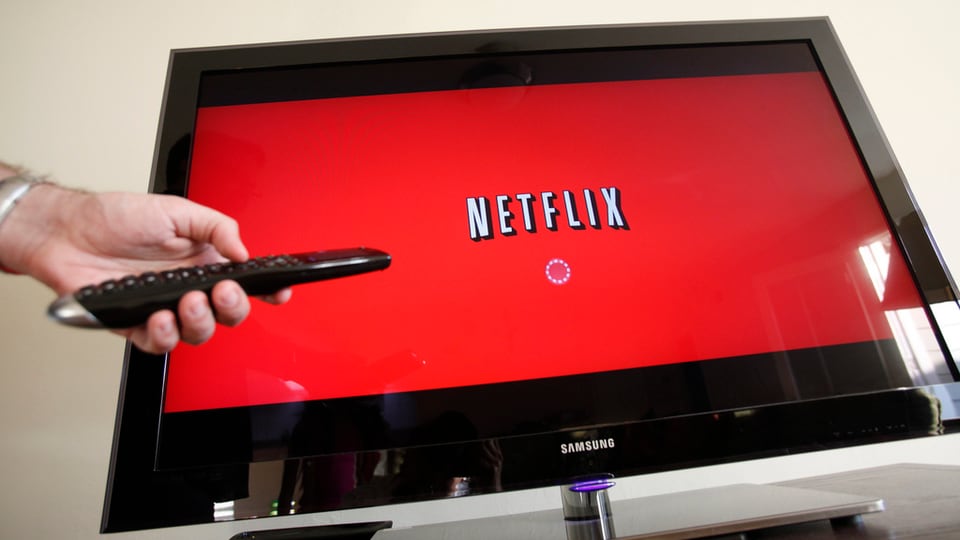 Ina televisiun cun il logo da Netflix ed in maun che tegna in telecumond. 