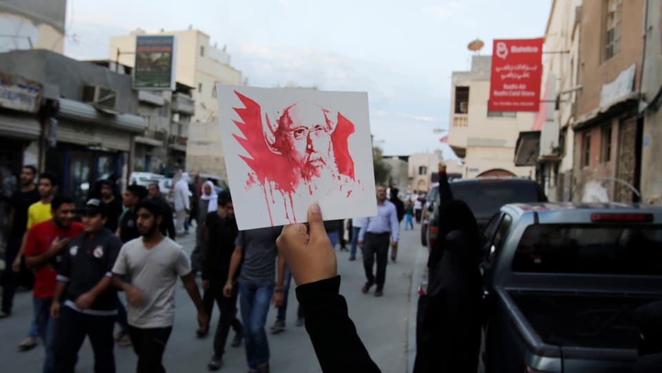 Ina persuna tegna ad aut in palpiri cun la fatscha dal spiritual Nimr Al-Nimr.