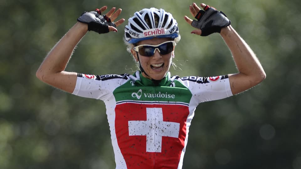 La ciclista da mountainbike Jolanda Neff giubilescha e tegna ad aut ses mauns.