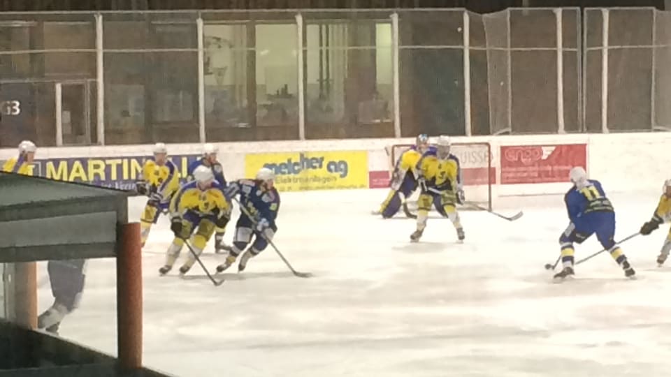 giugaders da hockey en tenues mellens e blaus dattan sin il glatsch a Ludains, San Murezzan