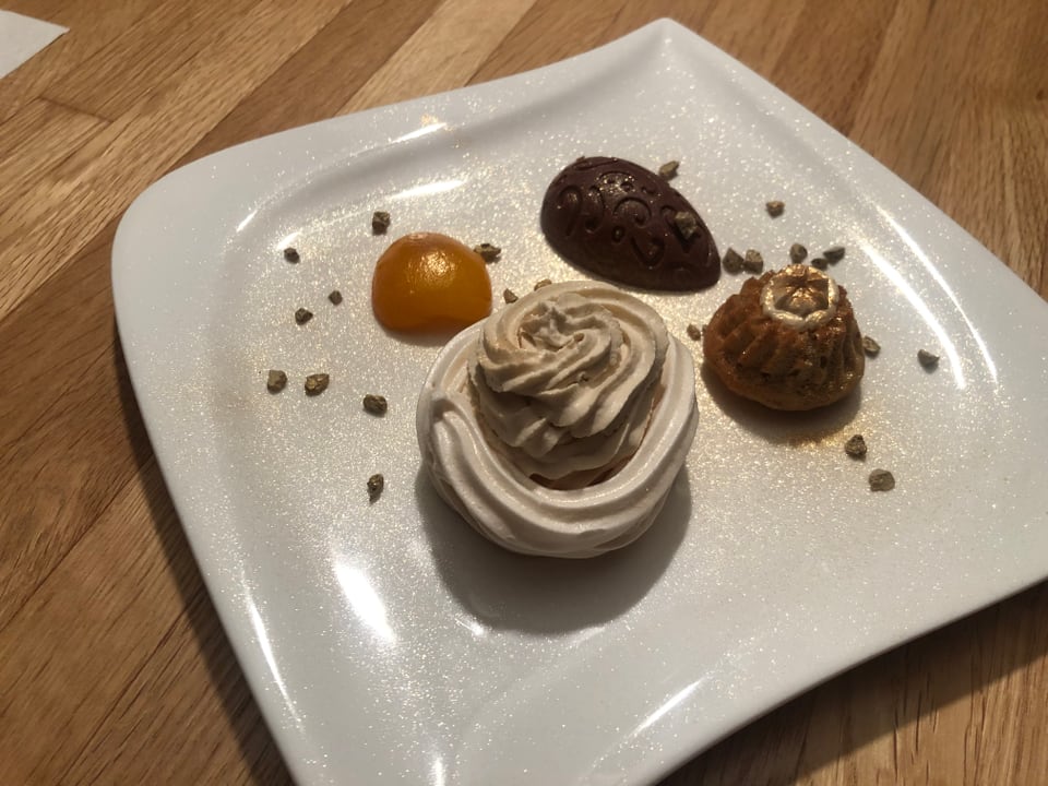 Dessertteller mit Meringue, Küchlein und Praline garniert mit Mocca und Sahne.