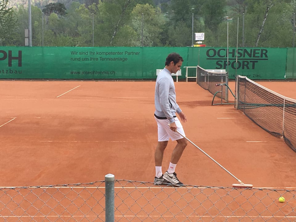 Roger Federer schubregia las lingias dal plaz da tennis a Favugn suenter il trenament.