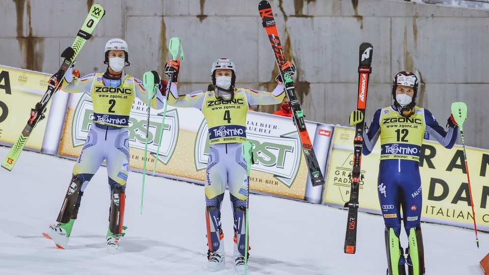 Trais skiunzs che tegnan ad aut lur skis e bastuns