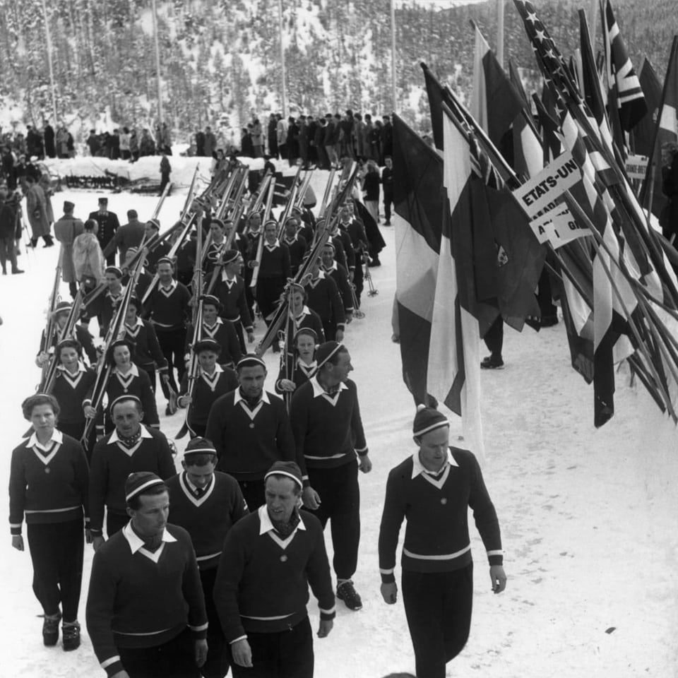 Sportists e sportistas en colonna, dasperas bandieras.