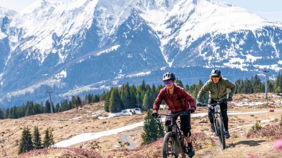 dus ciclists da muntogna davant ina cuntrada alpina