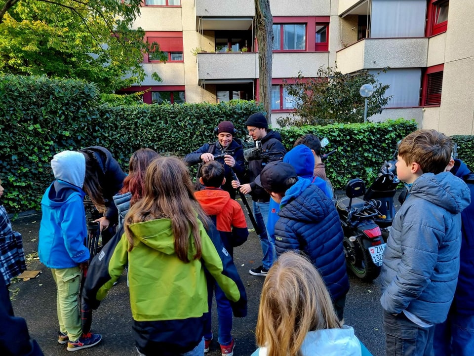 Eine Gruppe Kinder schaut zu wie eine Kamera eingerichtet wird.