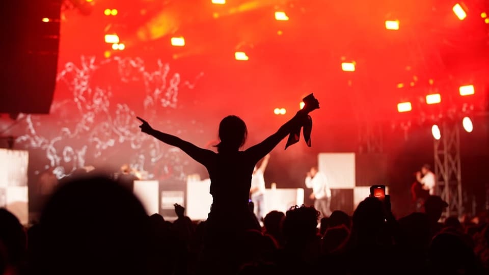 Chalender d'occurrenzas – Veranstaltungskalender RTR für Graubünden. Frau am OpenAir Konzert.