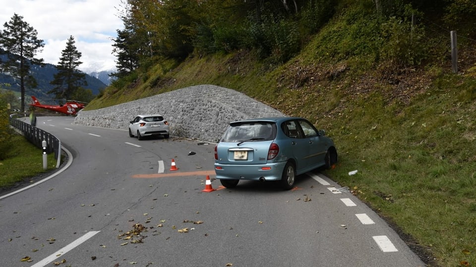 situaziun d'accident, dus autos stattan en via, davostiers in helicopter da la REGA