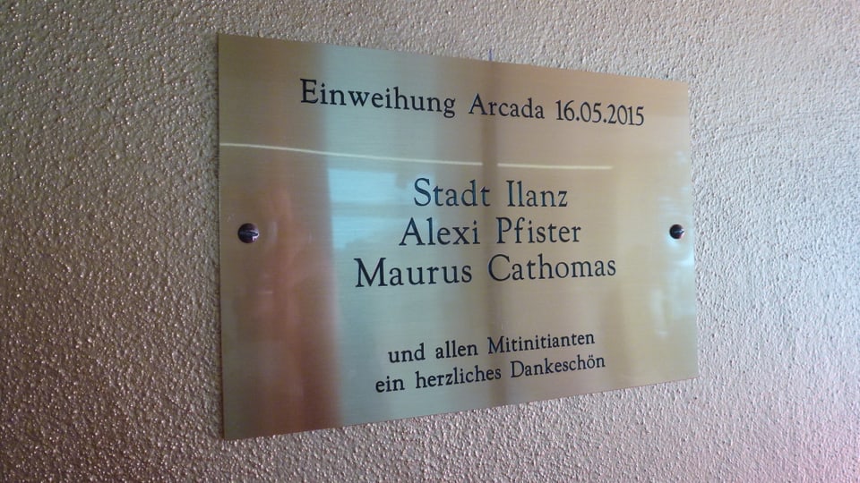 Ina tavla da metall cun scrit: "Einweihung Arcada 16.05.2015 - Stadt Ilanz, Alexi Pfister, Maurus Cathomas und allen Mitinitianten ein herzliches Dankeschön."