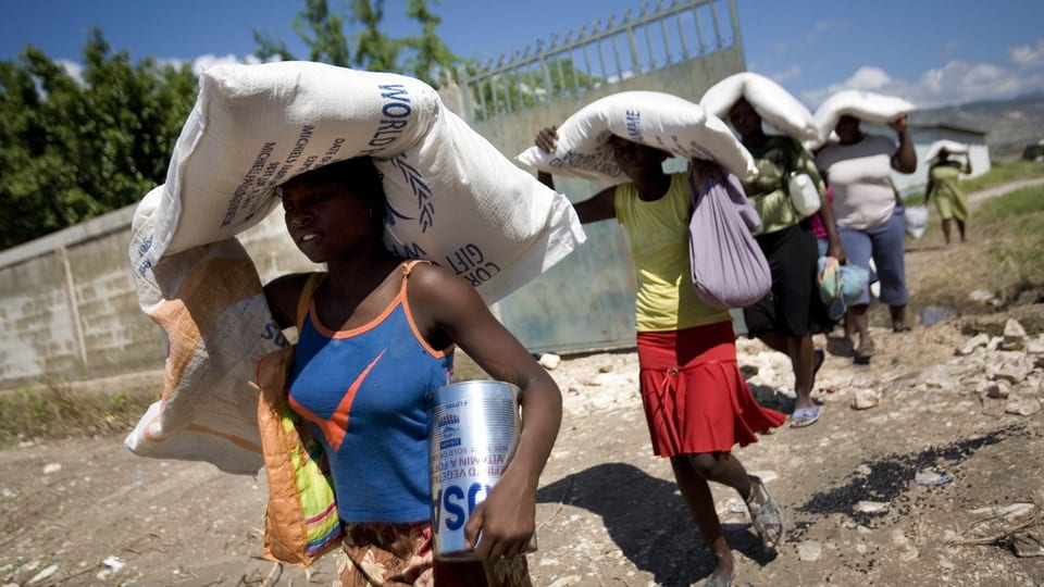 Persunas dal Haiti che portan satgs da nutriment. 