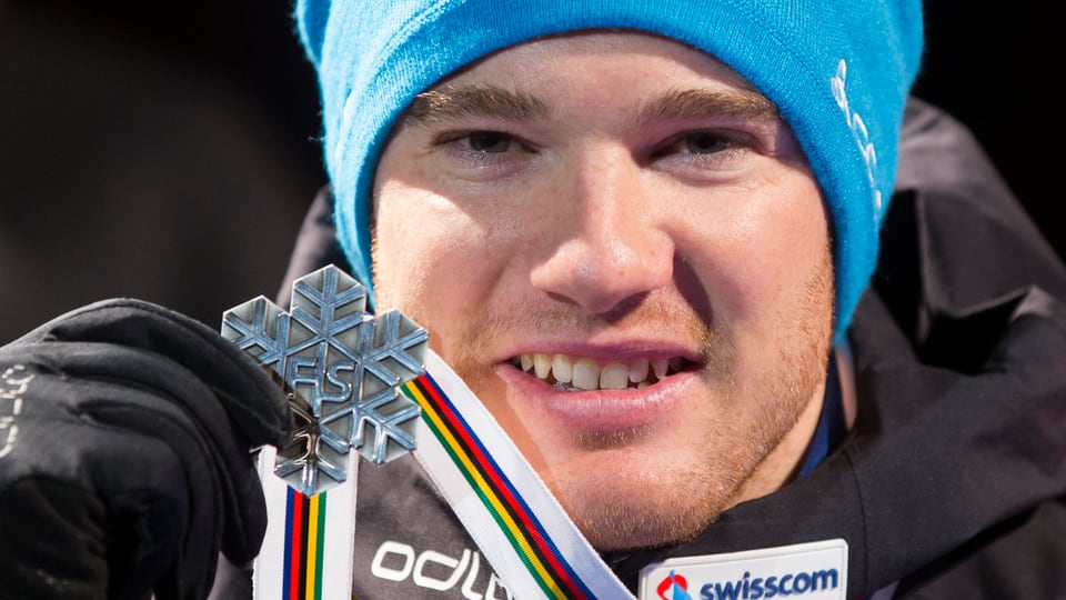 Dario Cologna che tegna sia medaglia d'argient.