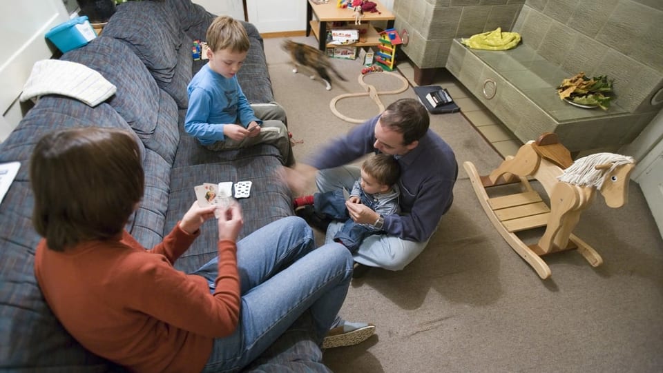 Purtret d'ina famiglia, bab, mamma, e dus uffants che sesan sin plantschieu e termaglian. 