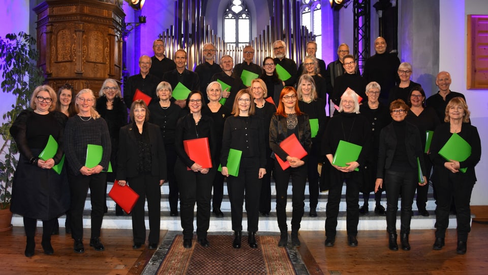 choR inteR kultuR,ein gemischter Chor, steht ganz in schwarz mit roten und gründen Notenmappen in einer Kirche