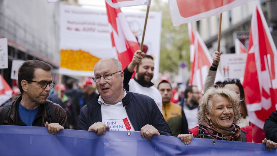 duas persunas che stattan davantvart cun in banner.