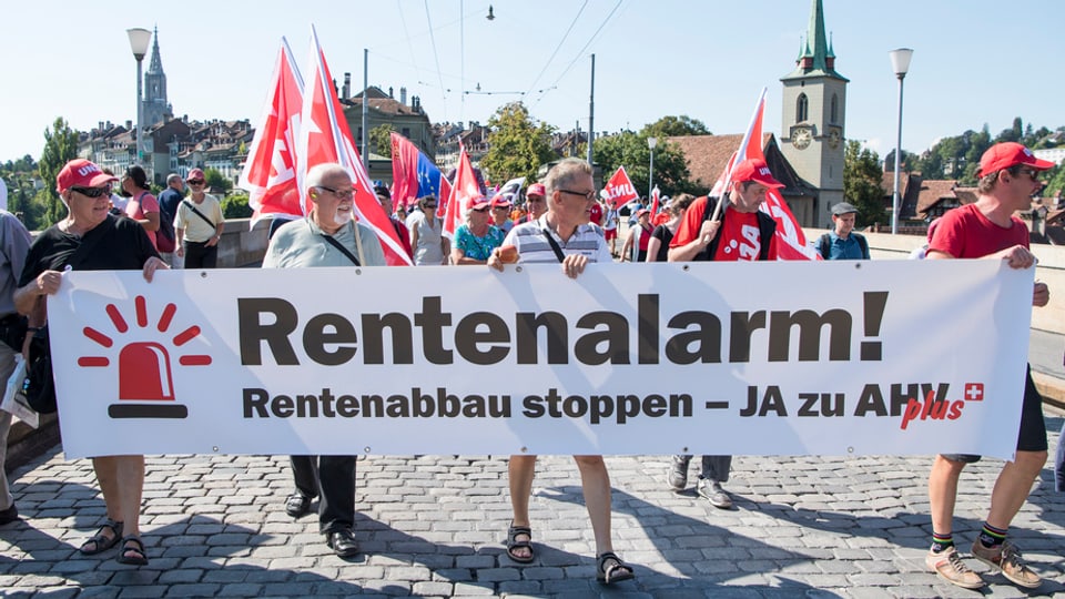 Demonstrantas e demonstrants cun in placat «Rentenalarm» a Berna.