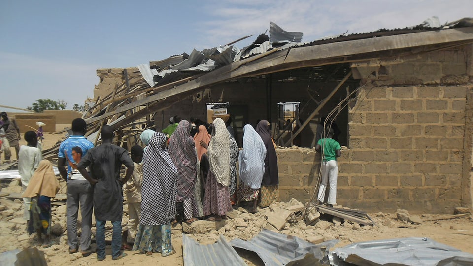 en la Nigeria, pliras persunas stattan avant ina chasa destruida
