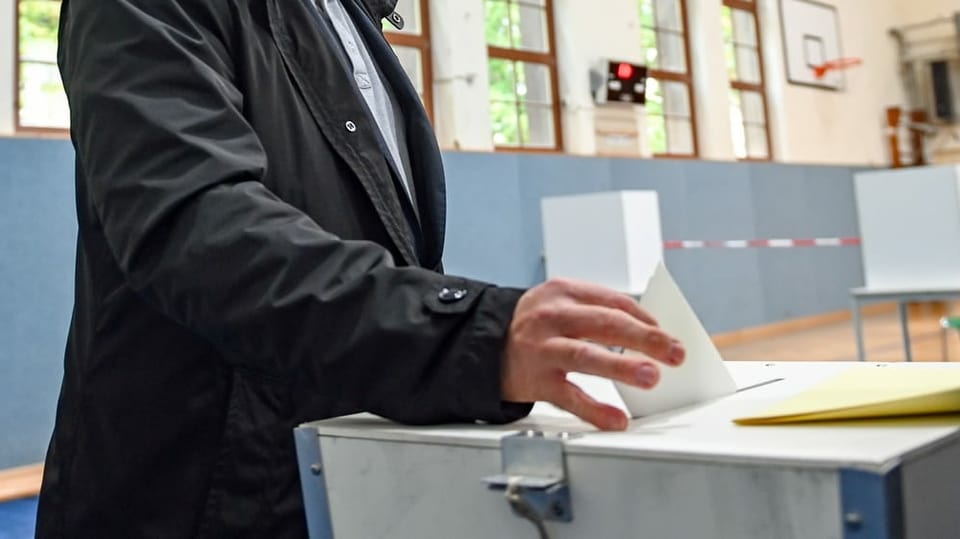 ina persuna che bitta gist ina brev da votar en in'urna.