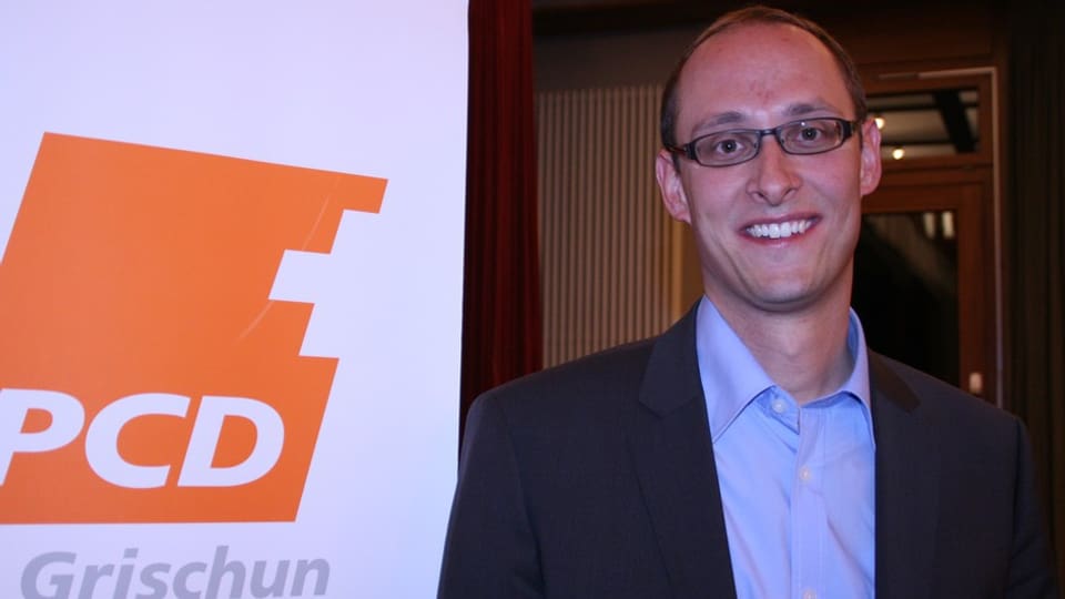 Martin Candinas avant il placat da la PCD Grischun.