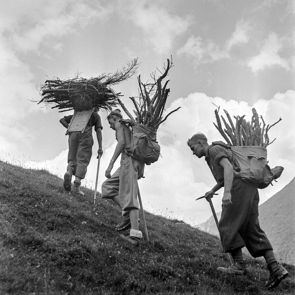 Fotografia en alv e nair da trais umens che portan laina en lur satgados si per ina stippa costa.