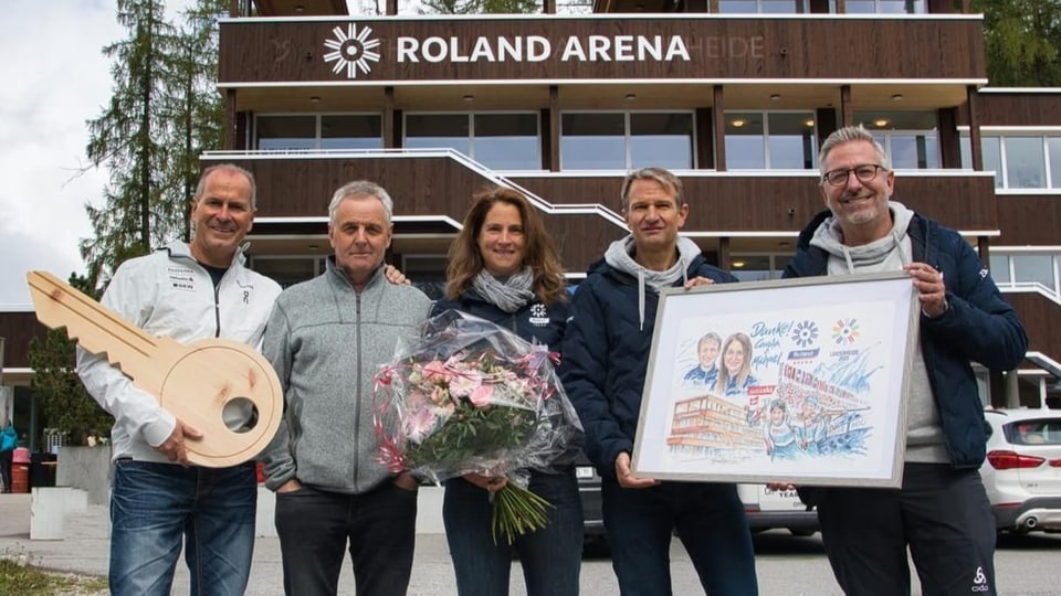 Ils responsabels mussan in maletg davant la Roland Arena, da vesair è il per che promova il biatlon fam. Hartweg.