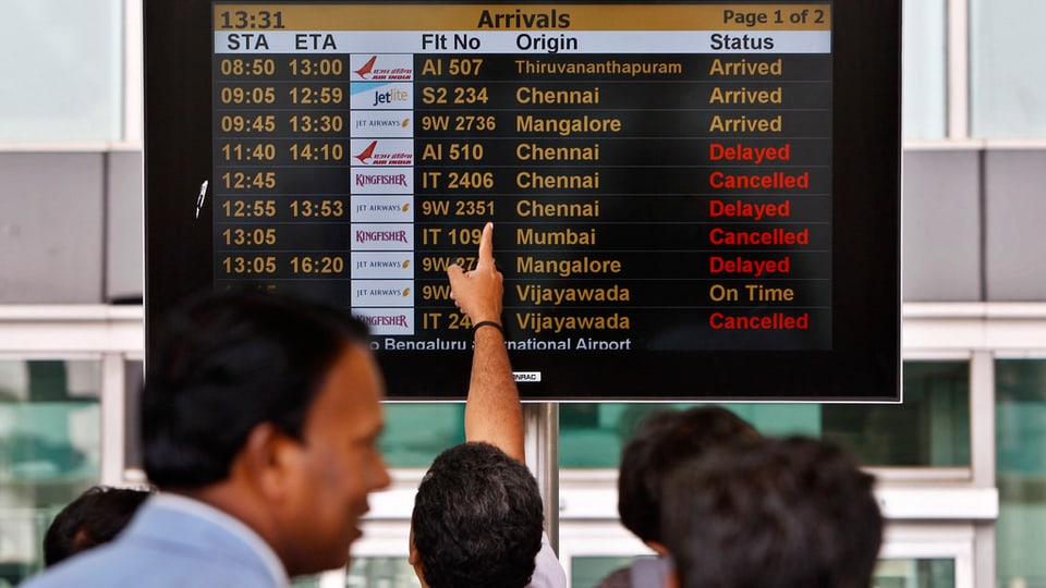 Eroport internaziunal a Bangalore (India) - pliras persunas stattan davant la tavla che mussa la partenza dals sgols