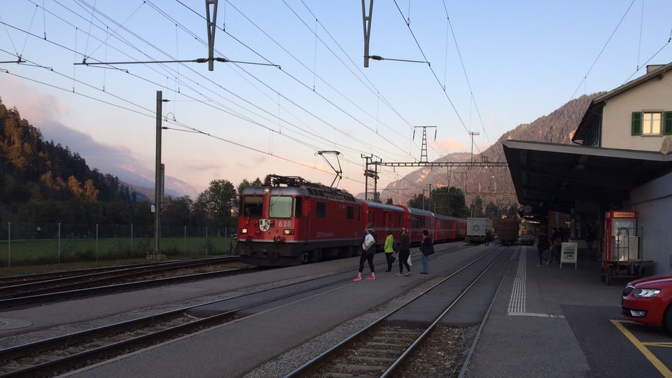 In tren charrescha en la staziun da Glion ils passagiers spetgan sin ils tren.