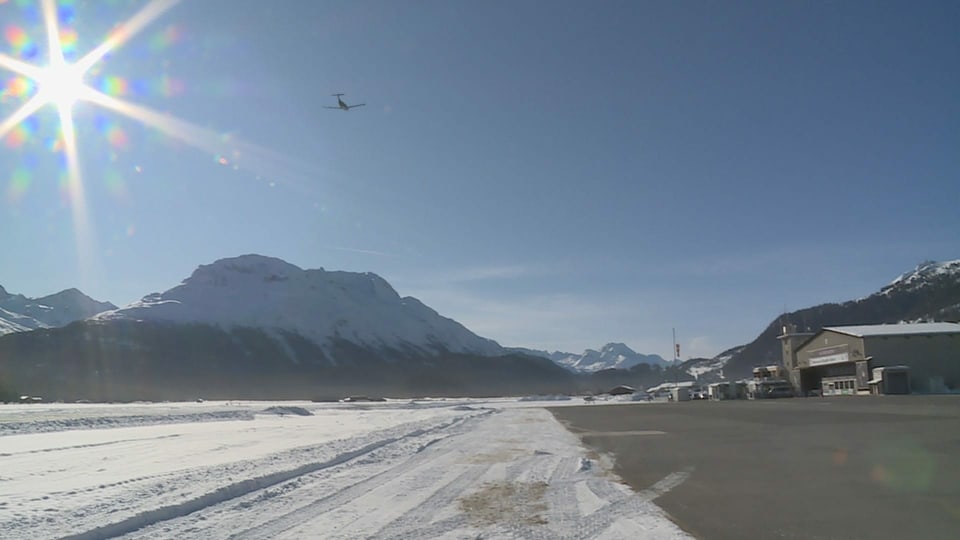 Vista sin la plazza aviatica - da la vart l'edifizi da l'Airport, davant la muntogna "La Margna" ed en il tschiel blau in aviun ch'è gista partì.