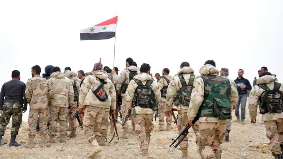 Schuldads sirians van cun la bandiera siriana vers la citad da Palmyra
