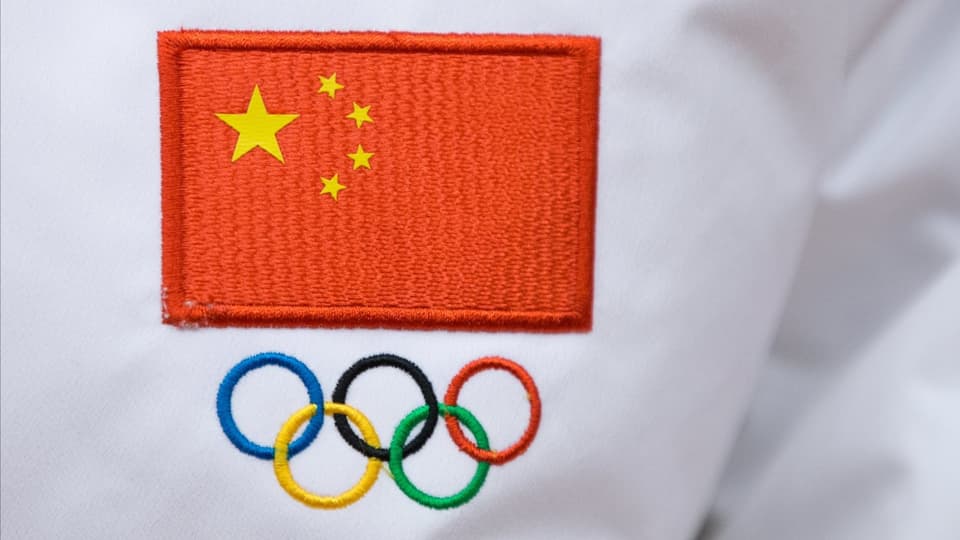 in pulllover cun cusì si la bandiera cotschna cun stailas da la China e sutvi ils rintgs olimpics.