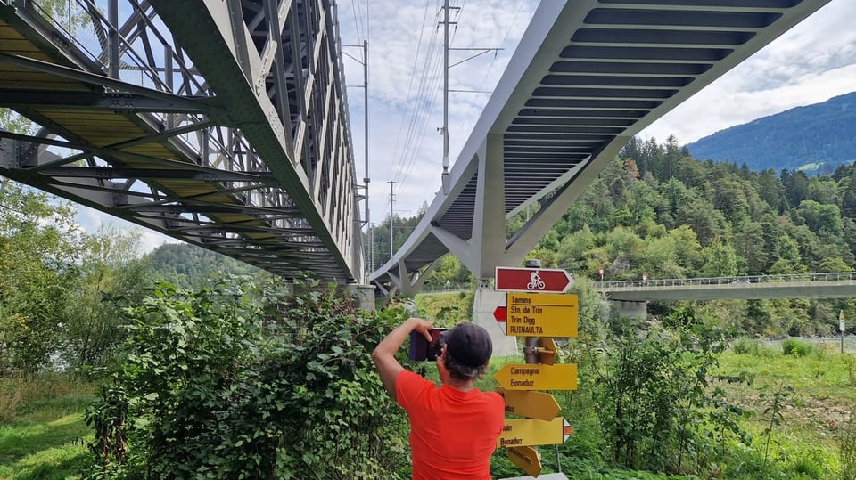 Eine Frau fotografiert zwei nebeneinanderstehende Brücken.
