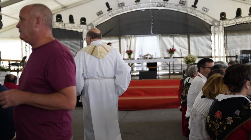 Der Priester auf dem Weg zur Bühne für die Messe im Festzelt.