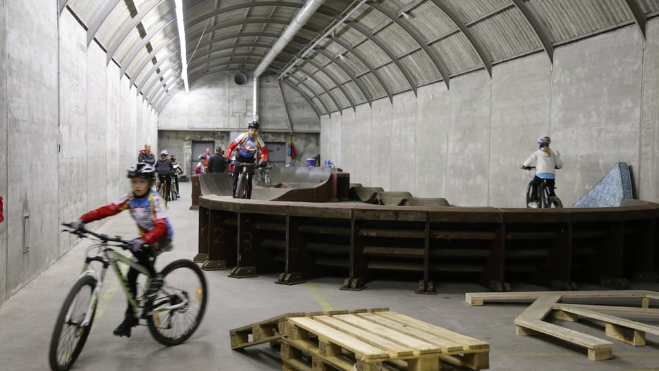 Ciclists che van cun lur velos en ina halla sin in "pump track".