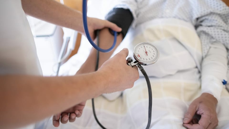Maun da tgirunza che mesira il squitsch dal sang a pazienta en letg d'ospital. 