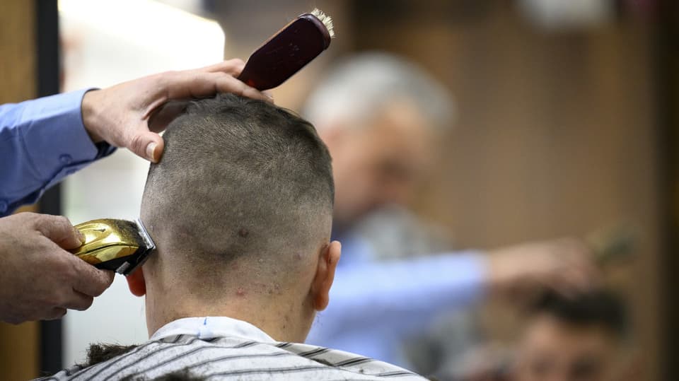 Ein Mann lässt sich mit der Maschine die Haare schneiden. 