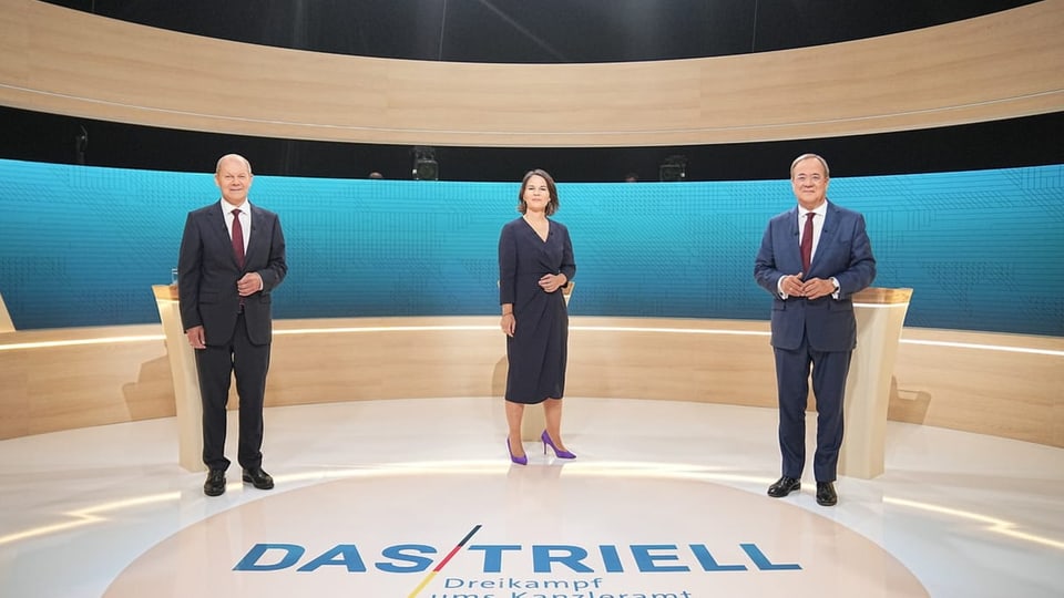 purtret dals trais sco els stattan en retscha davant il pult.