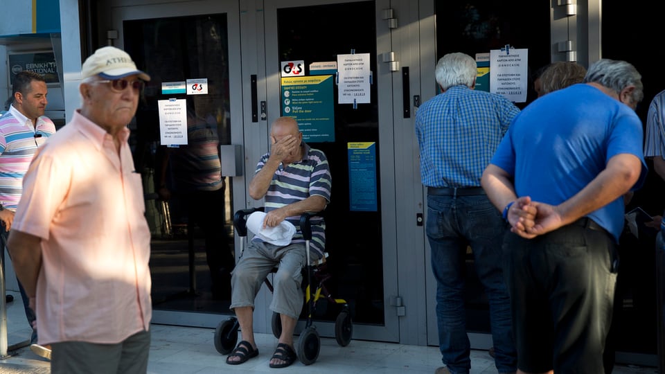 Persunas attempadas spetgan avant ils eschs serrads d'ina banca greca.