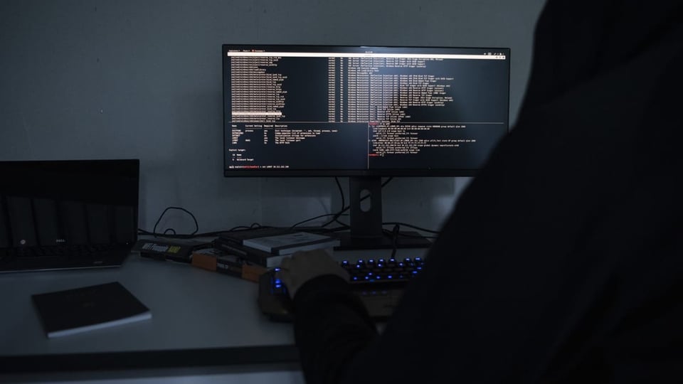 Ein Hacker sitzt vor dem Computer, der Bildschirm ist voller Zeichen.