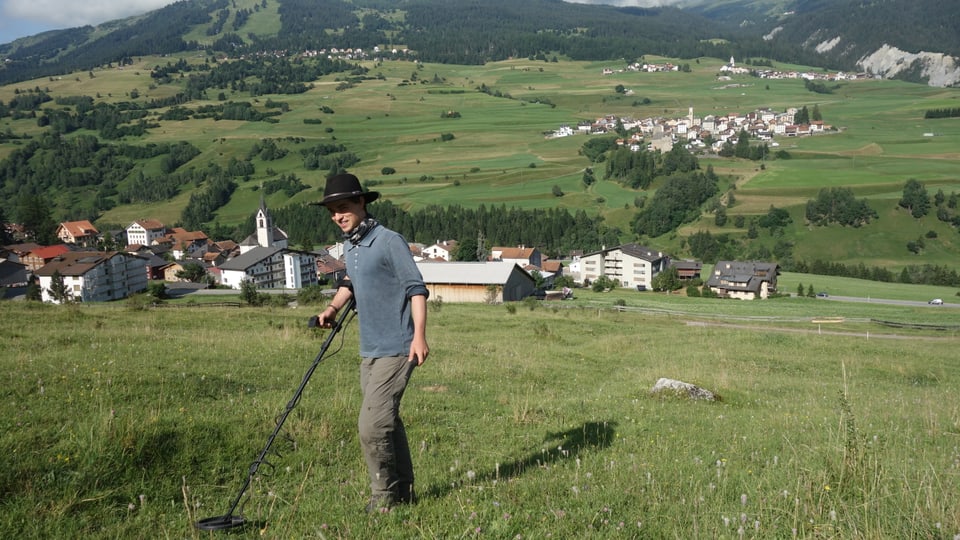 Simon Kurmann, il student da l'Universitad da Turitg examinescha il terren sur Cunter cun in detectur da metal.