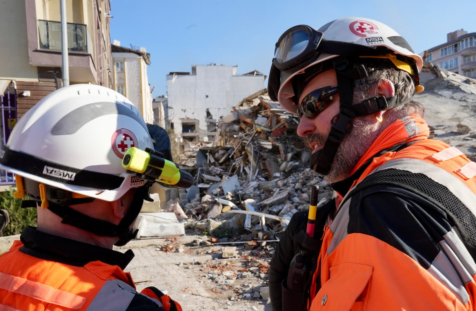  Zwei Rettungskräfte vor zerstörten Häusern.