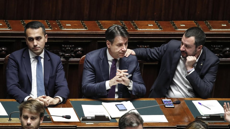 Purtret dals trais che sesan en il parlament in dasper l'auter. 