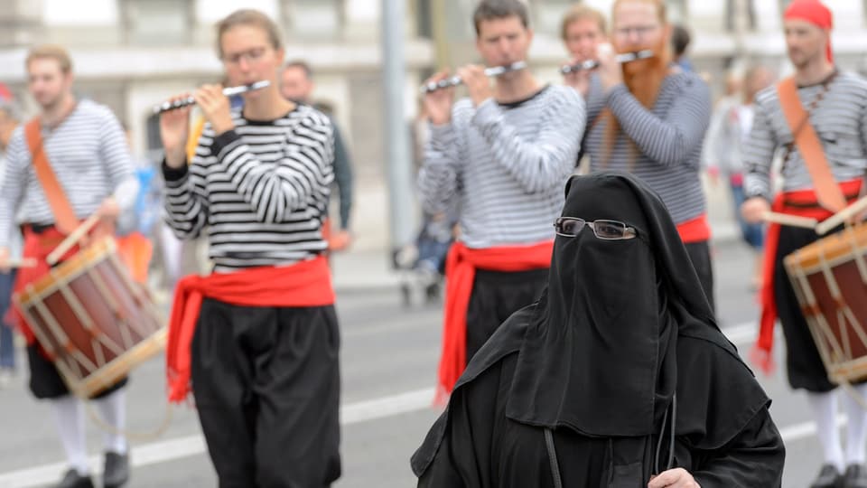 Dunna che porta il nikab avant ina gruppa da tamburs. 