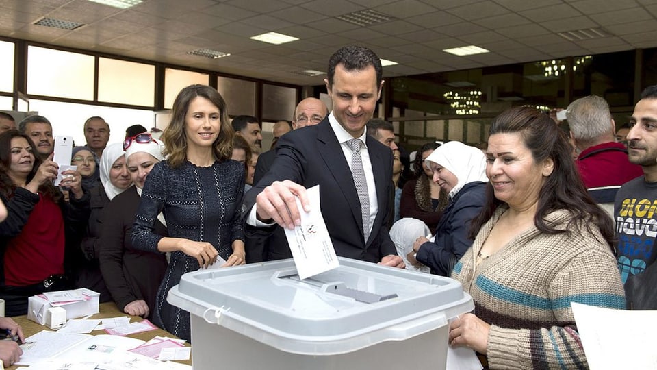 Il maletg mussa co Baschar al-Assad metta il cedel da votar en l'urna.