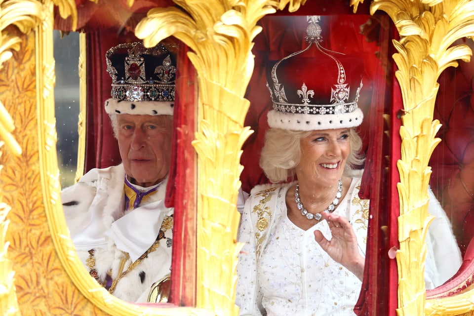 Charles und Camilla in der königlichen Kutsche winken dem Volk zu