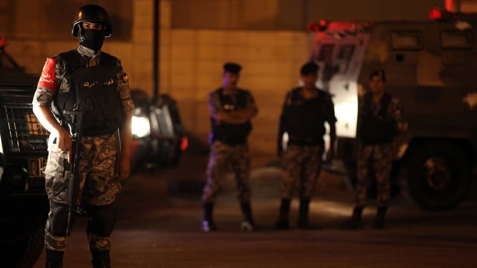Purtret dad in policist che stat davant in auto cun in'arma. 