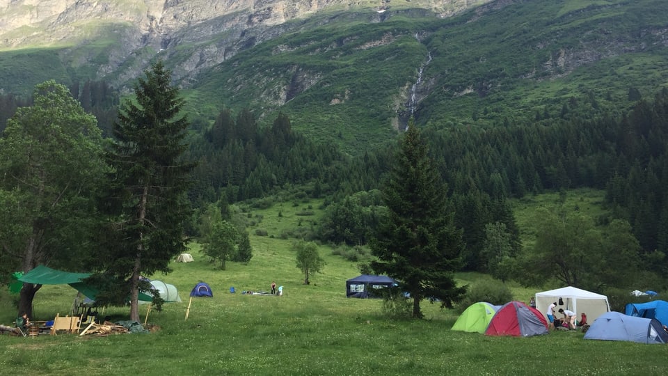 Ina culissa da muntogna e guaud alpin cun intginas tendas.