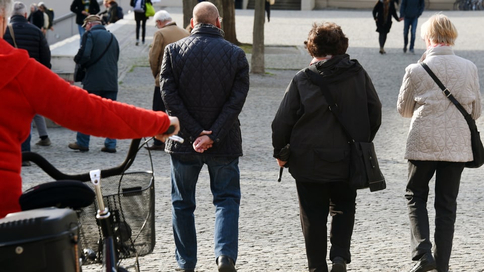 seniors che van a pe tras ina via d'ina citad