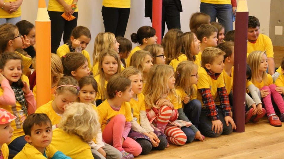 uffants da scola stattan en schanuglias, tuts portan in t-shirt mellen