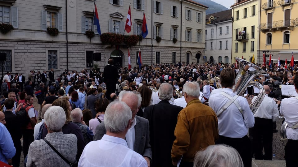 Purtret da la plazza cun massa persunas che spetgan. 