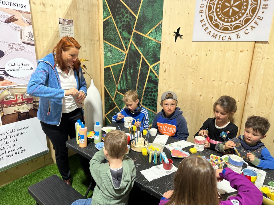 Kinder bemalen Keramiktassen an einem Tisch